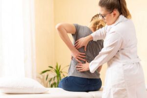 A chiropractor reviewing a spine model with a patient in a comfortable clinic setting.