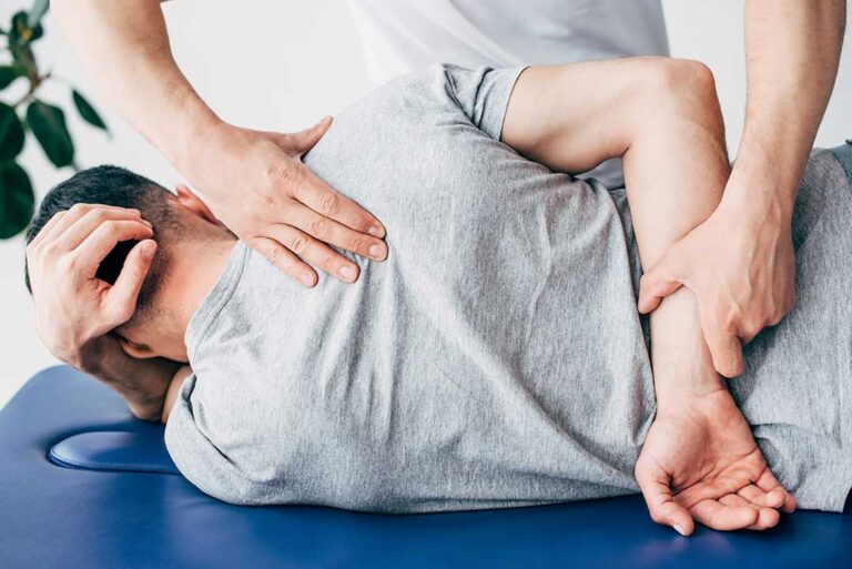 Person gently stretching their back at home in a well-lit living room with comfortable furnishings.