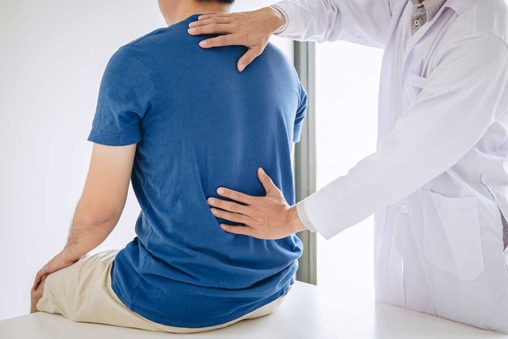 Person sleeping comfortably on a bed with a pillow supporting the knees while a clinician reviews a posture diagram.